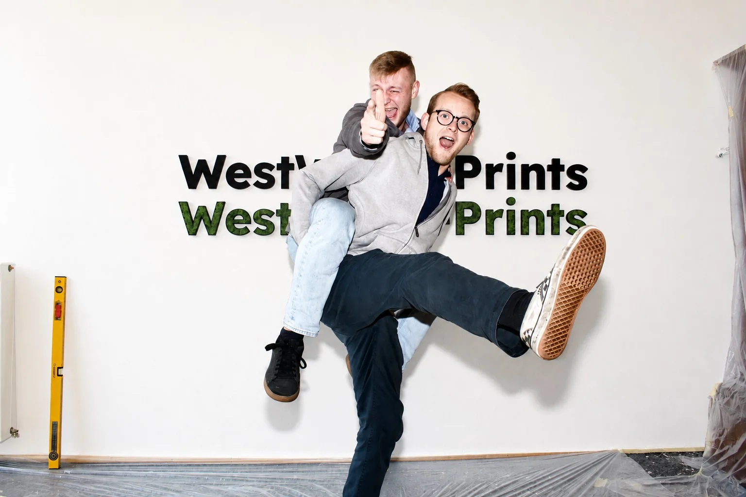 Bild der beiden Geschäftsführer von WestWood-Prints in einem Raum vor zwei 3D-gedrucken Wandlogos